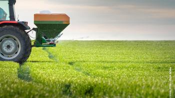 a tractor spreading fertilisers on a green field