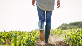 image from the back of a farmer wearing boots and walking in the field