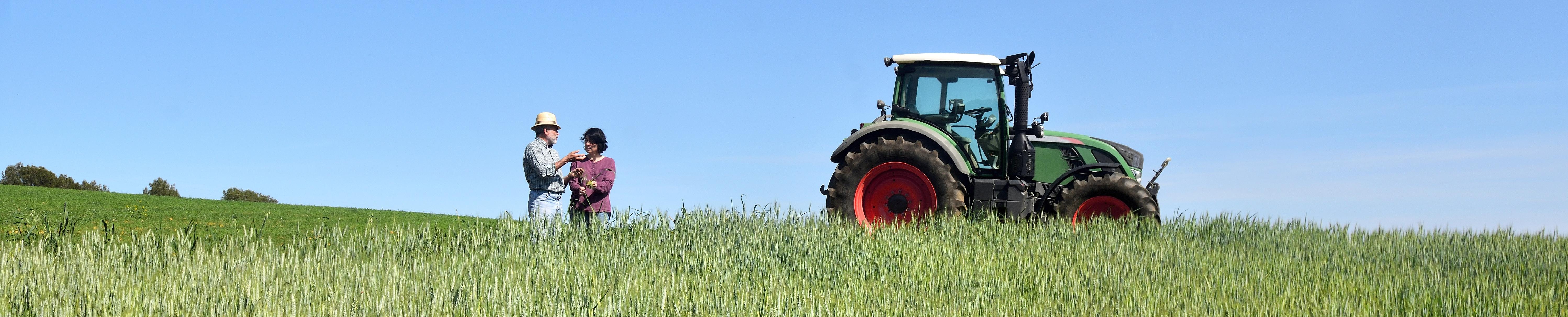two farmers in a field next to a tractor