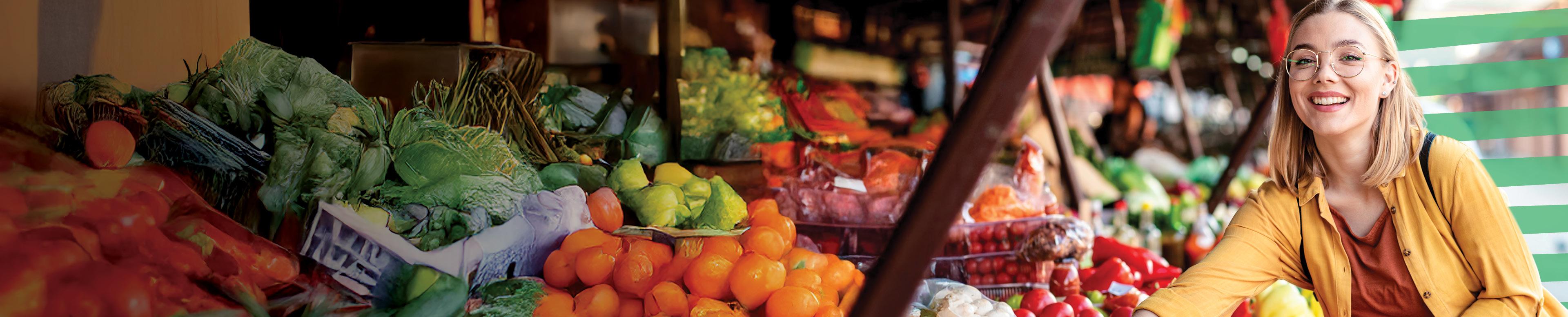 young woman at the market in front of vegetables and fruit stands