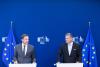 two men standing in front of lecterns at a press conference
